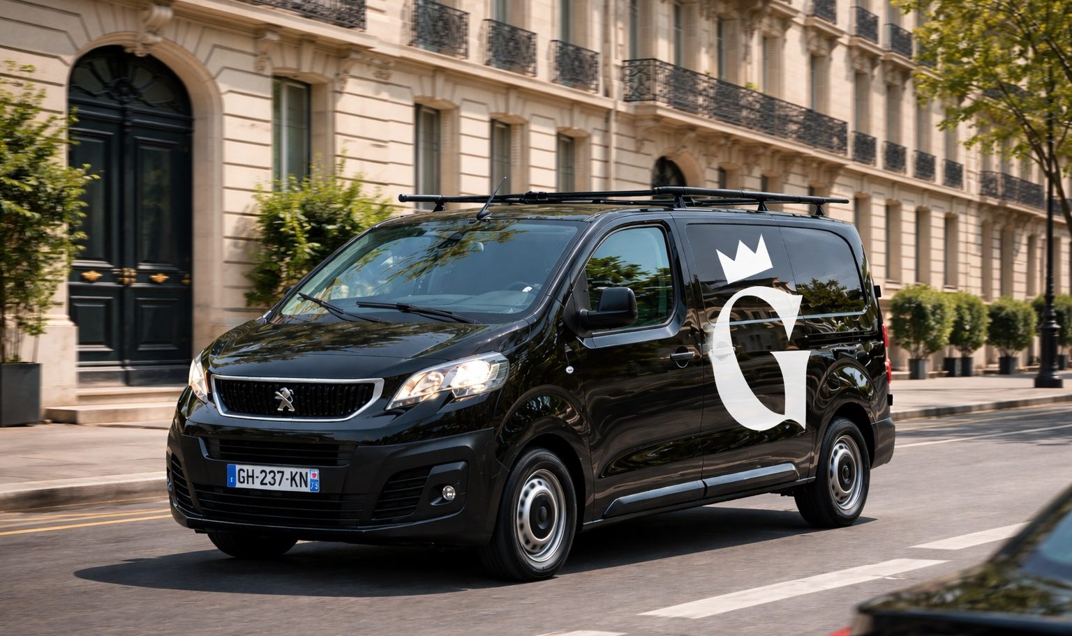 Gaston - Truck Fourgon noir avec un grand "G" blanc, garé sur une rue bordée d'arbres.